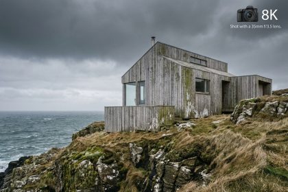 Maison ossature bois en bord de mer avec bardage en cèdre grisé par le sel, perchée sur une falaise rocheuse face à l'océan Atlantique